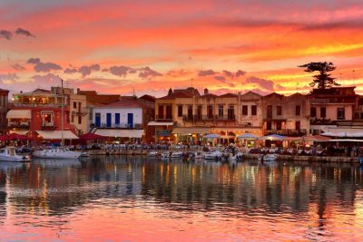 A picturesque view of Rethymnon harbour with boats and colourful buildings in the background.