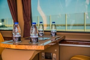 Four bottles of water on a table inside a Luxurious black Mercedes minibus